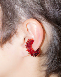 Detail view of red glass ear cuff, highlighting the pattern of dots and tiny spheres along the curve.