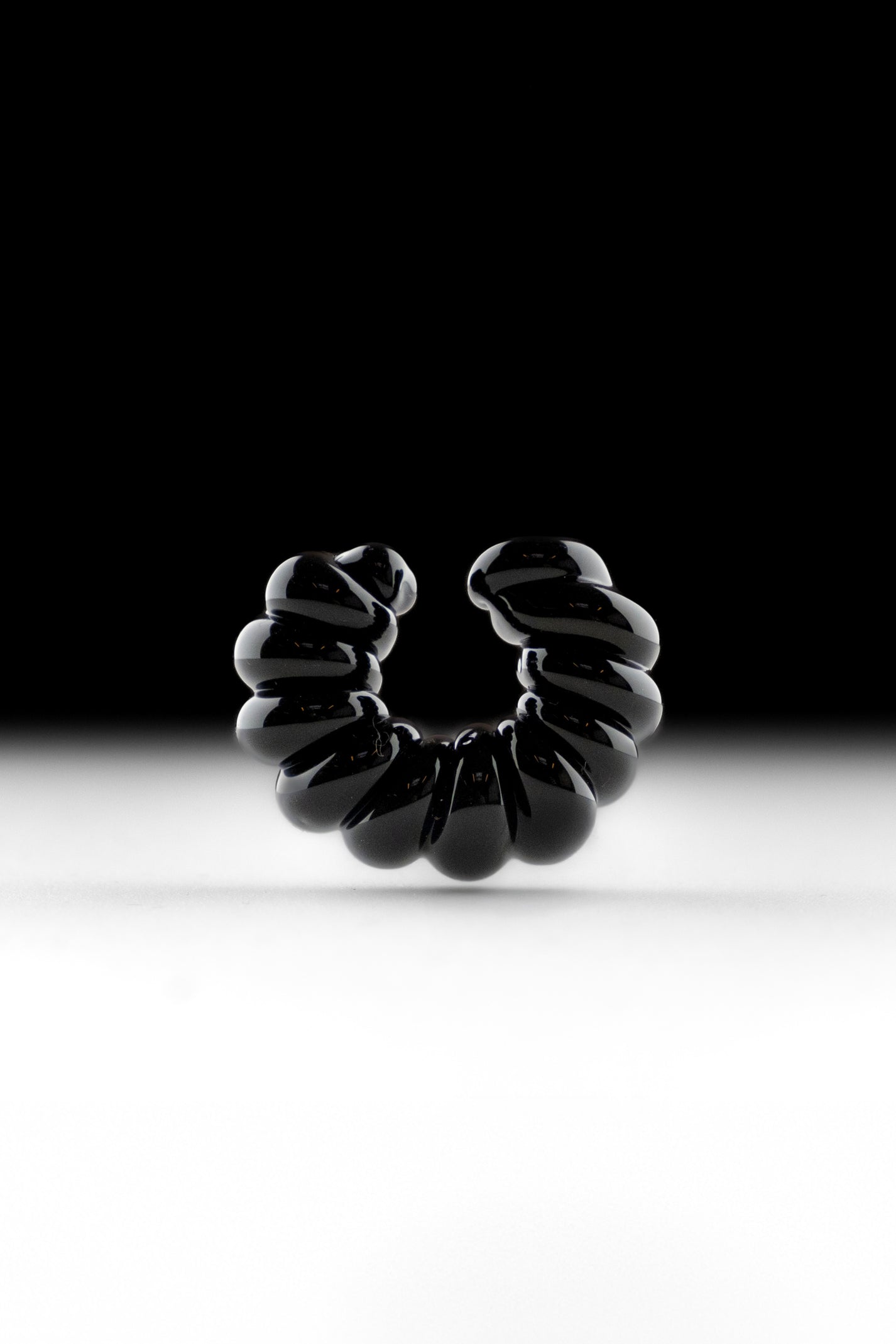 Black borosilicate glass ear cuff, shaped by hand into a continuous twist.