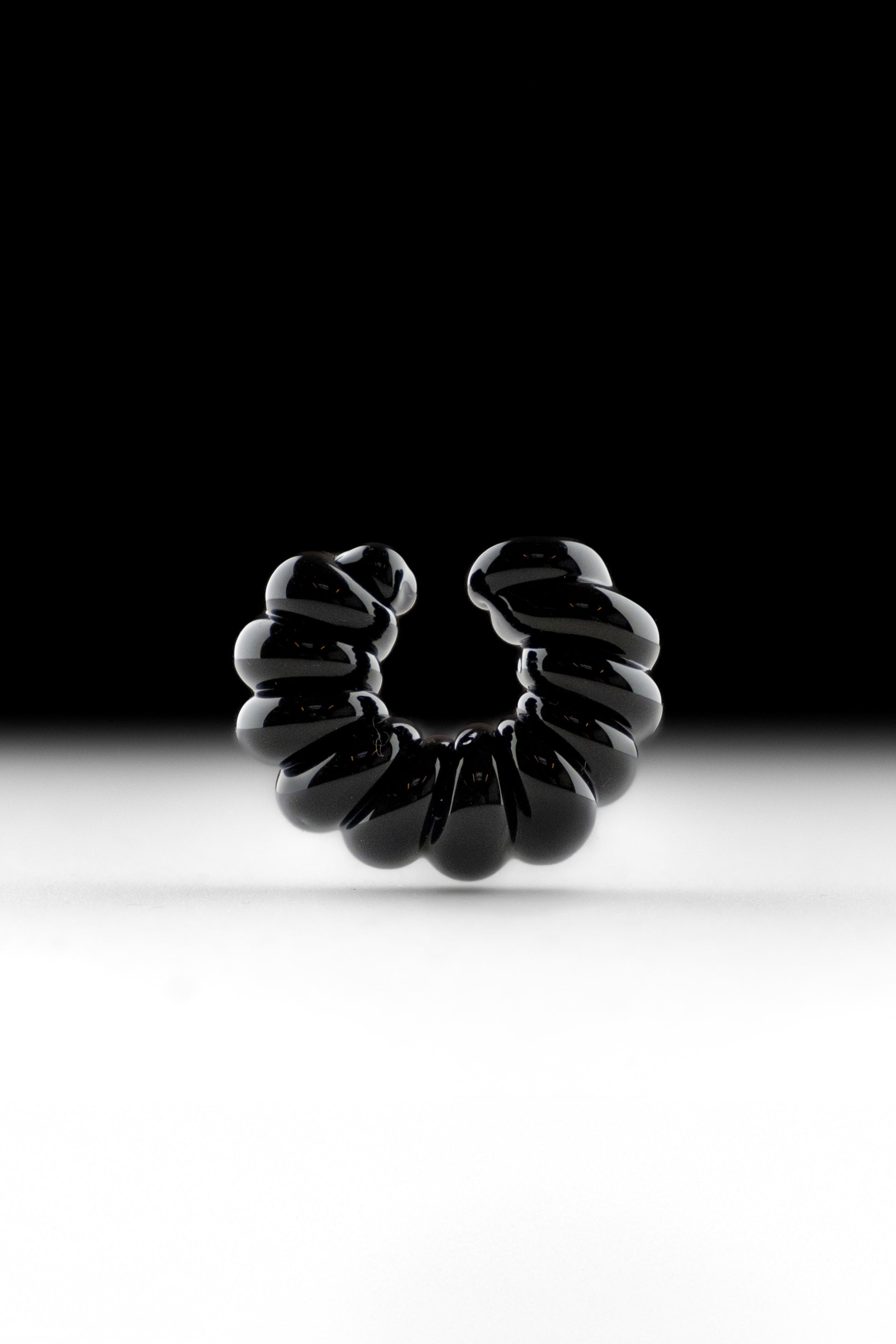 Black borosilicate glass ear cuff, shaped by hand into a continuous twist.