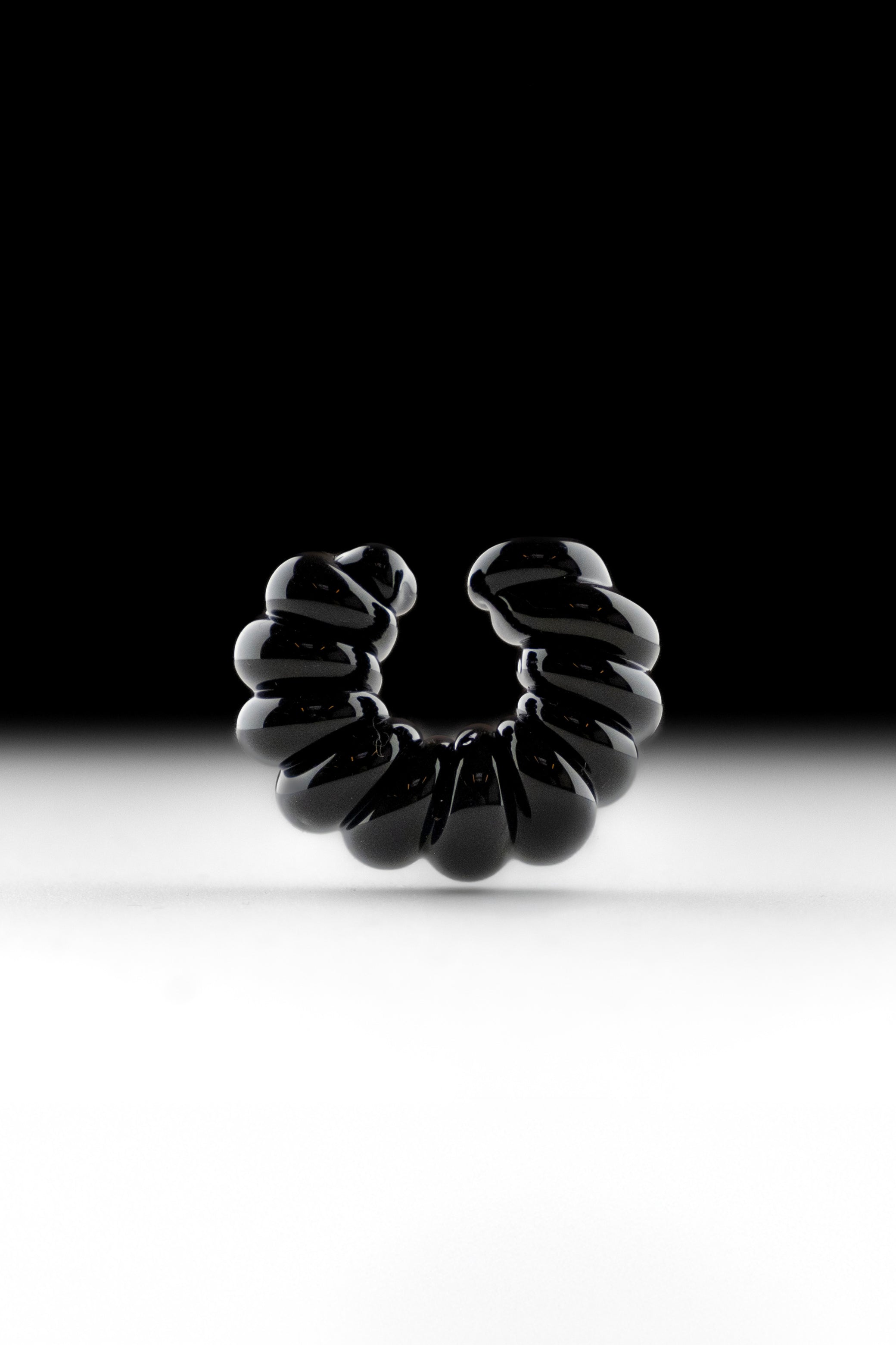 Black borosilicate glass ear cuff, shaped by hand into a continuous twist.