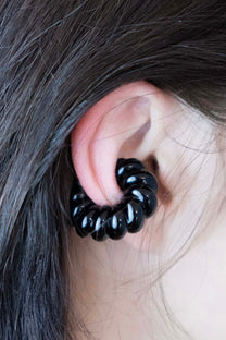 Handcrafted black glass ear cuff shown on ear, sculptural form, fits without piercing.
