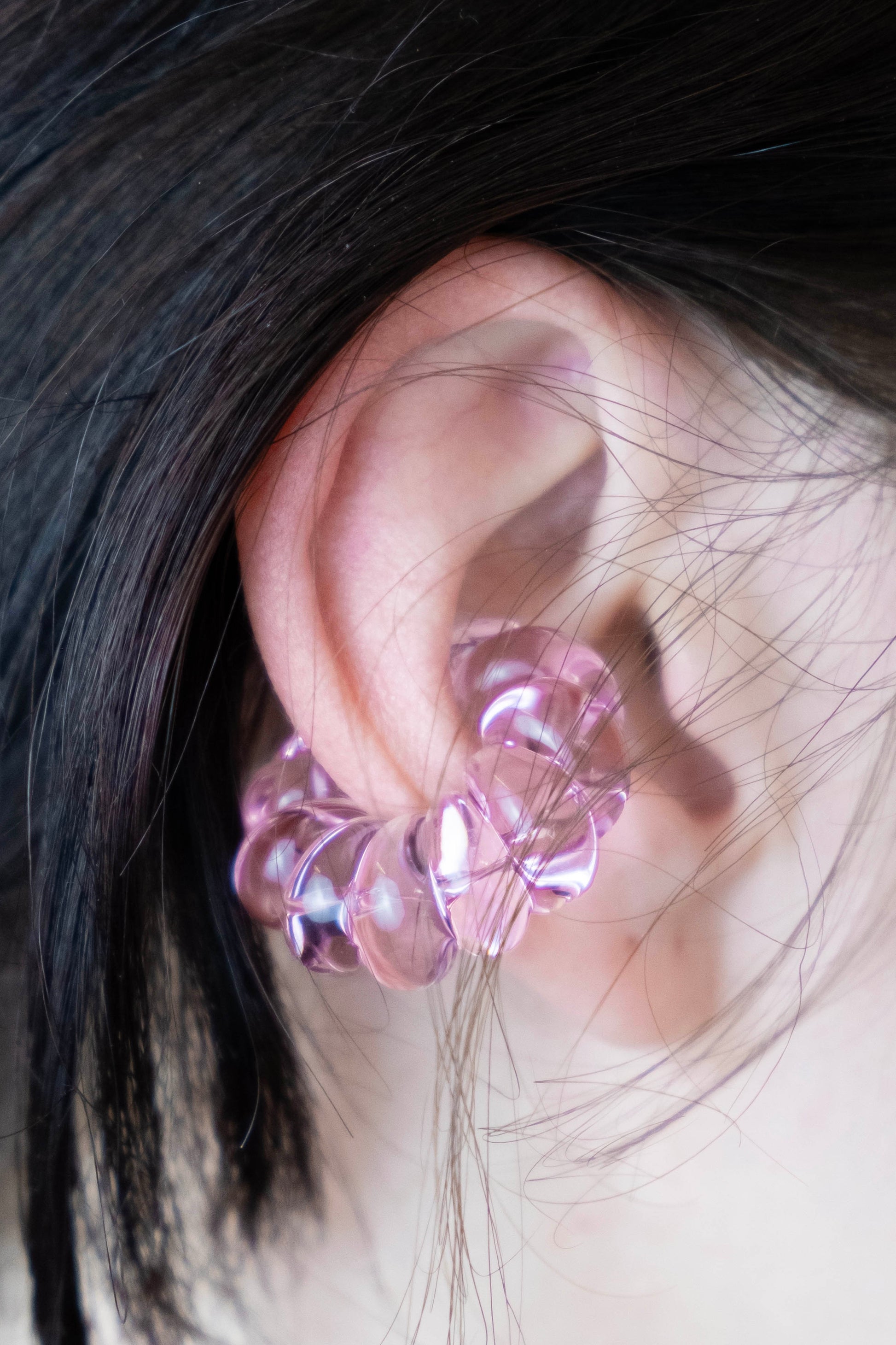 Handmade pink glass ear cuff on ear, sculptural twist, non-pierced wear.